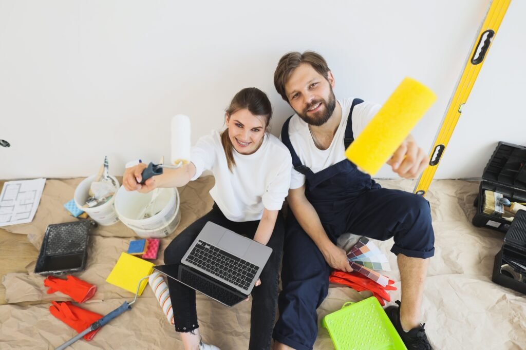 Joyful young wife and husband family couple sit on floor in new apartment during renovation process